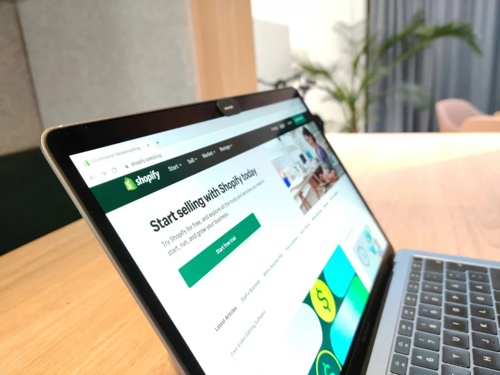 Laptop displaying Shopify website with start selling online page open on a workspace desk