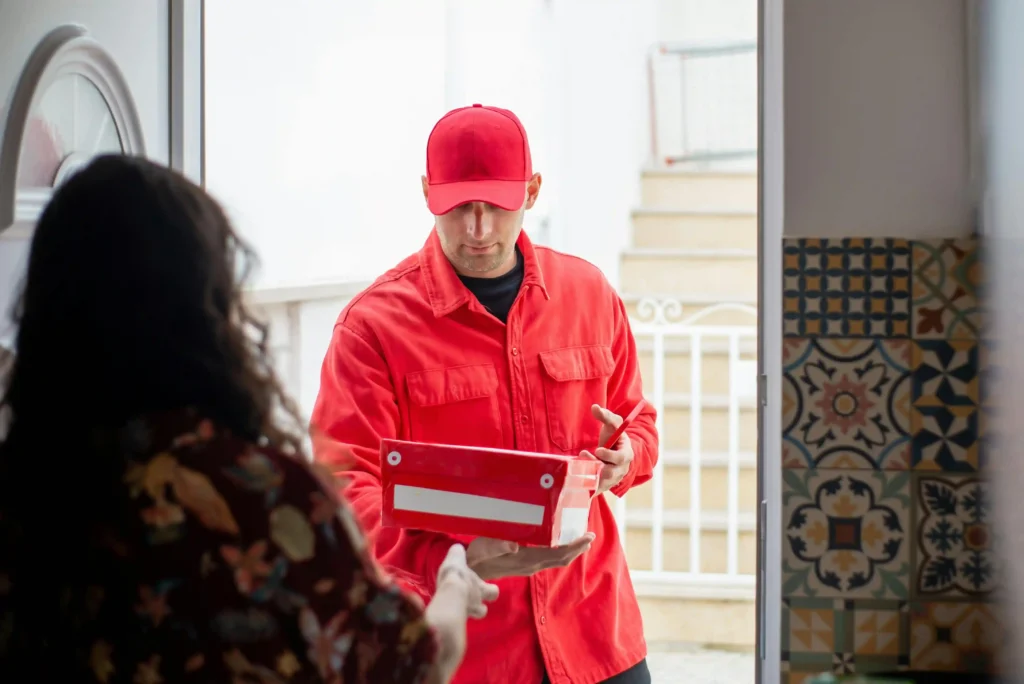 customer is receiving the product from the shipper the shipper is wearing red uniform