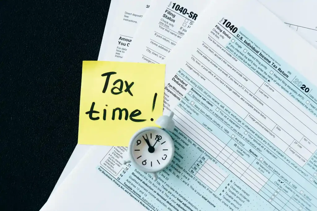"tax time" is written on the yellow sticky note under that sticky note there are some documents of taxes
