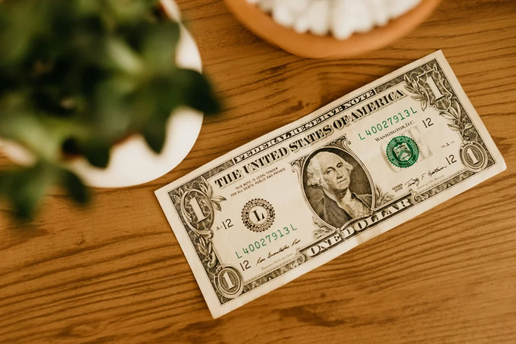 Close-up image of a one-dollar bill placed on a wooden table, symbolizing online earnings, Fiverr seller fees, freelance income, and payment deductions for beginners in 2026.